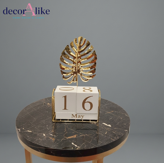 Perpetual desk calendar with gold monstera leaf topper on side table – Decoralike Lahore