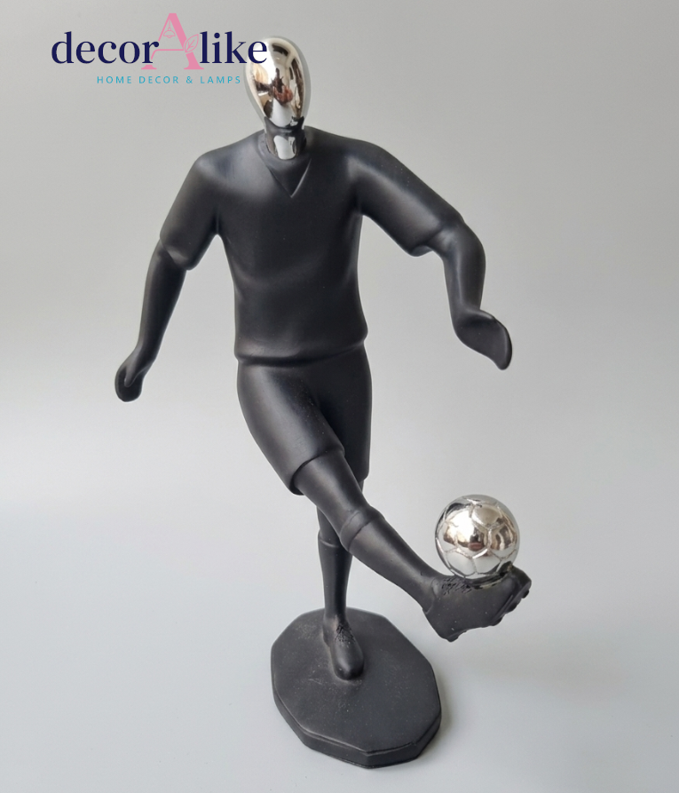 A modern black soccer player figurine with a reflective silver head and soccer ball, standing on a matching black base against a light gray background. The 'decorAlike' brand logo is visible in the top left corner.