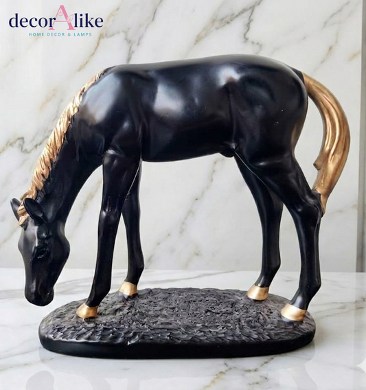 A glossy black horse figurine with gold-colored mane, tail, and hooves, standing on a textured dark base against a white marble background. A 'decorAlike' brand logo is visible in the top left corner.