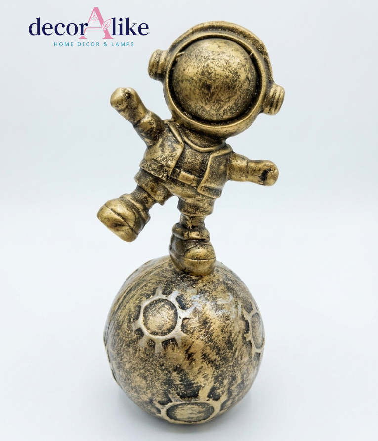 Antique gold astronaut statue balancing on textured moon sphere decor piece