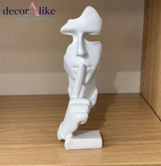 Modern white abstract face sculpture with shh finger gesture