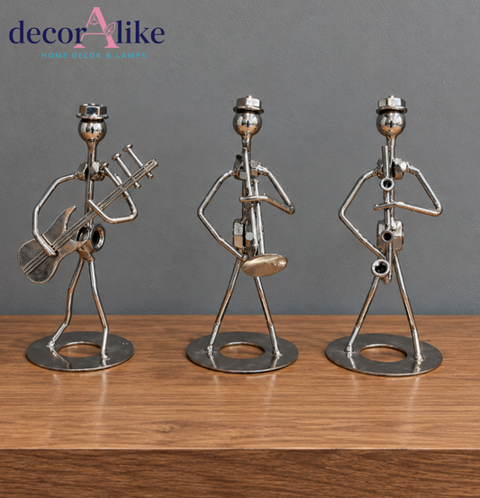 Set of three metallic musician figurines with musical instruments on wooden shelf