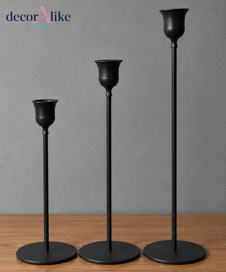 Set of three black metal candle holders in different heights on wooden table