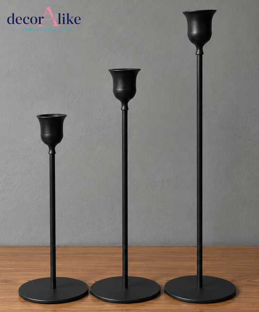 Set of three black metal candle holders in different heights on wooden table