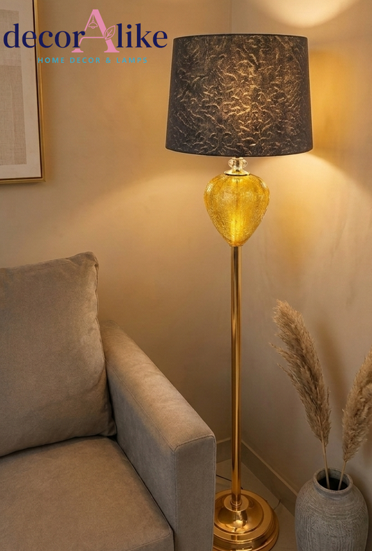 Gold crystal floor lamp with amber glass teardrop base 
and textured charcoal shade glowing in living room corner