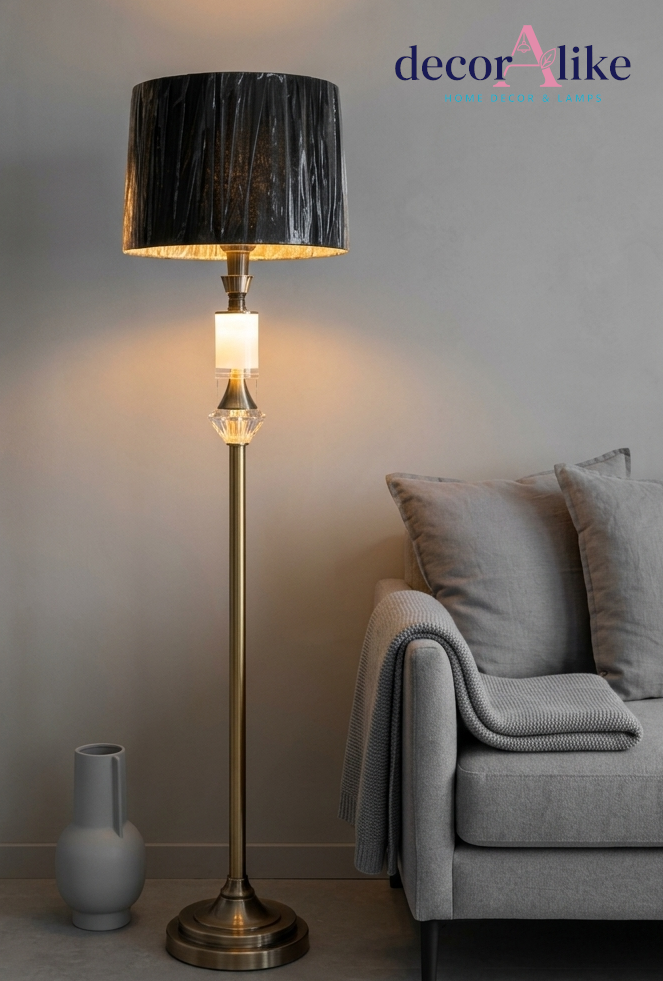 Gold brass crystal accent floor lamp with pleated charcoal shade beside a grey throw