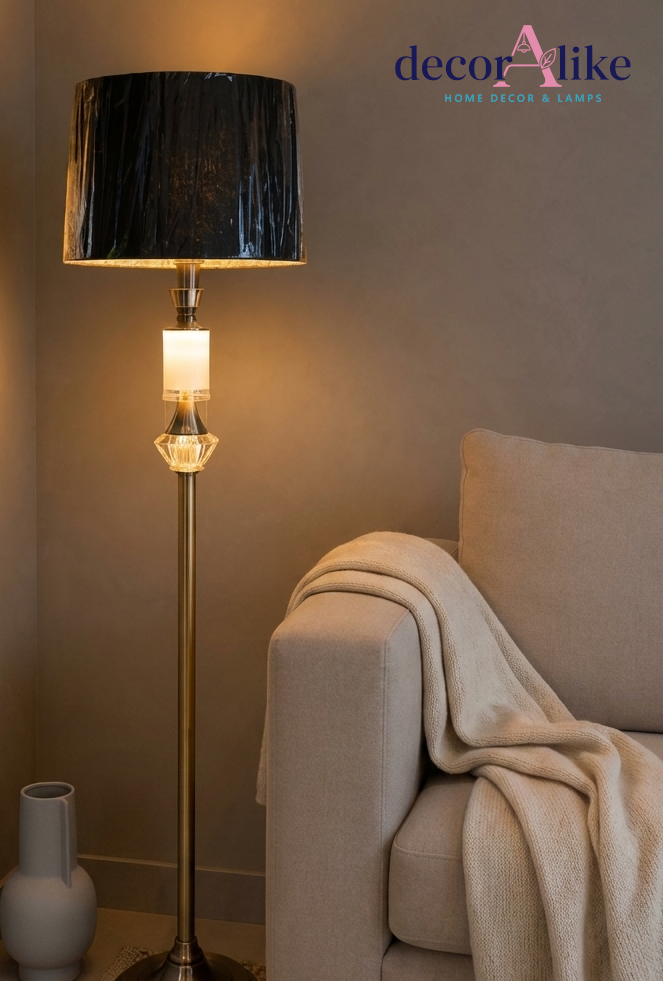 Gold brass crystal accent floor lamp with pleated charcoal shade beside a grey throw