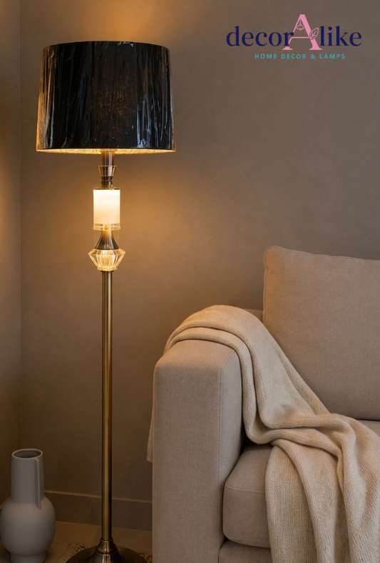 Gold brass crystal accent floor lamp with pleated charcoal shade beside a grey throw
