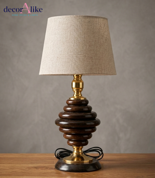 Stacked wood ring table lamp with dark wood base, brass accents, and beige linen shade on wooden table - DecorAlike Pakistan
