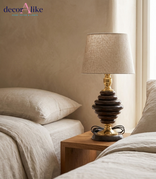 Stacked wood table lamp with beige shade glowing on bedside table in cozy bedroom setting - DecorAlike Pakistan