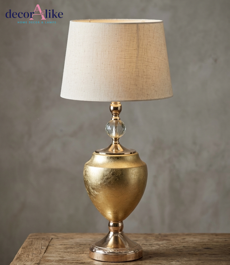 Luxury gold urn table lamp with crystal accent and beige linen shade on rustic wooden table - DecorAlike Pakistan