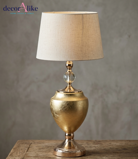 Luxury gold urn table lamp with crystal accent and beige linen shade on rustic wooden table - DecorAlike Pakistan