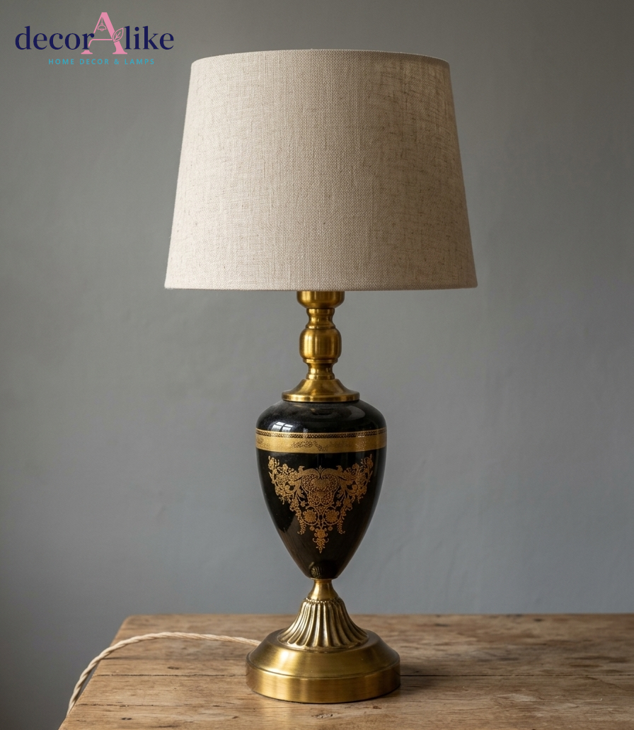 Black and gold ornate urn table lamp with intricate detailing and beige linen shade on wooden table - DecorAlike Pakistan