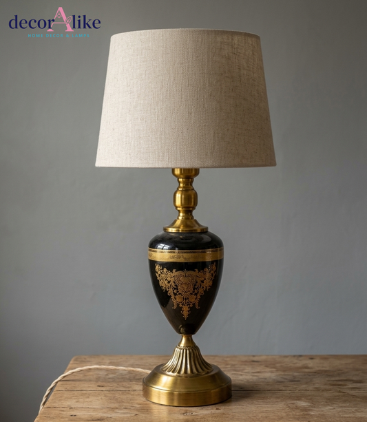 Black and gold ornate urn table lamp with intricate detailing and beige linen shade on wooden table - DecorAlike Pakistan