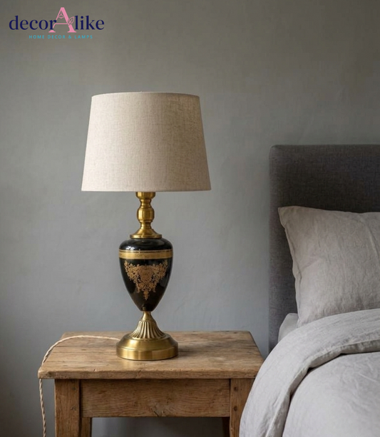 Black and gold ornate urn table lamp with intricate detailing and beige linen shade on wooden table - DecorAlike Pakistan