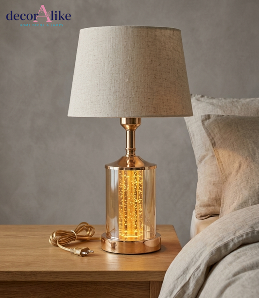 Modern gold bubble glass table lamp with glowing filament effect and beige linen shade on wooden table - DecorAlike Pakistan