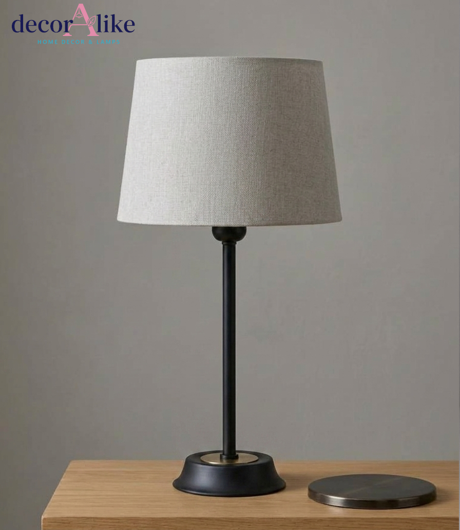 Minimalist matte black slim stem table lamp with brass ring detail and grey linen shade on an oak console