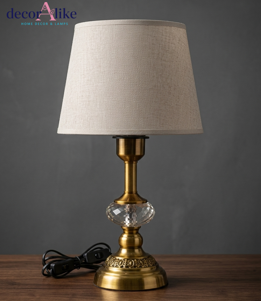 Antique brass table lamp with faceted crystal detail, embossed filigree base and beige linen drum shade
