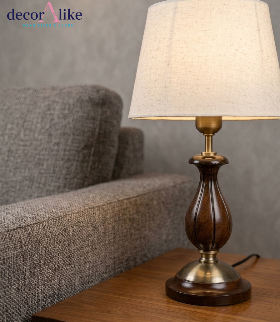 Carved wooden table lamp in walnut finish with brass accents and ivory linen shade on a wooden side table