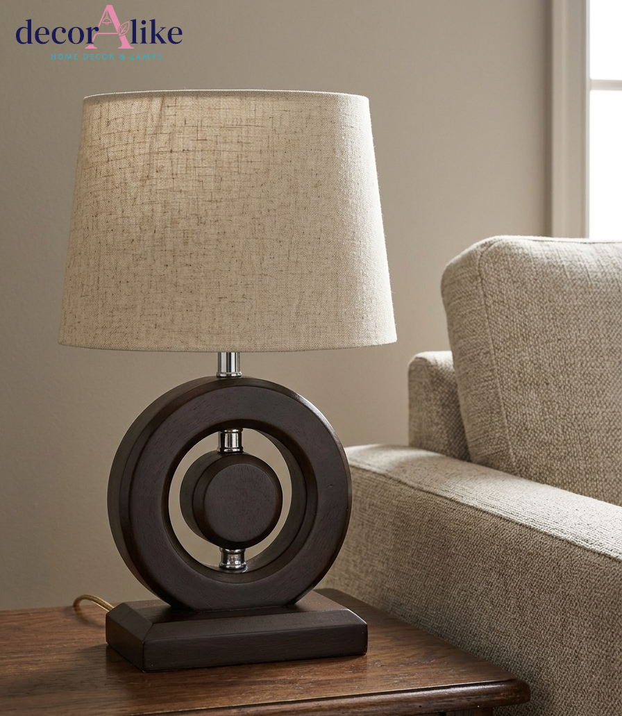 Modern walnut-finish wooden ring table lamp with chrome accents and beige linen drum shade on a wooden table