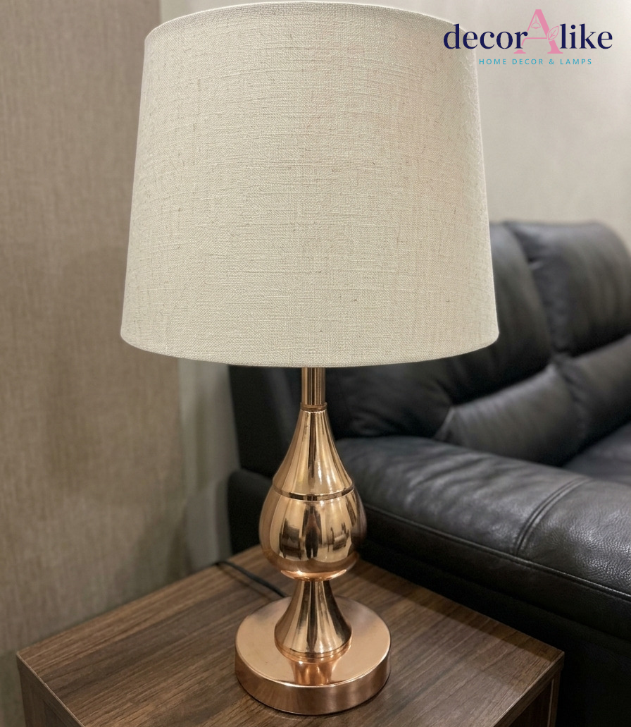 Modern rose gold table lamp with beige linen shade on wooden side table — bedside lamp Pakistan