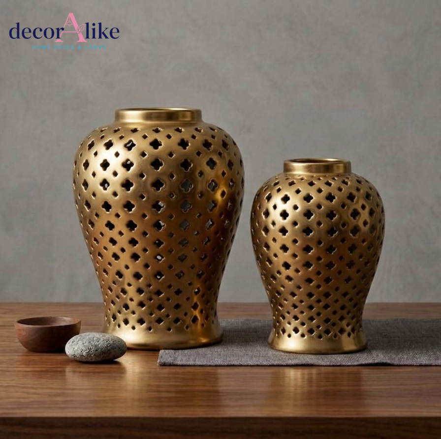 Two golden ceramic decorative vases with geometric l cutouts, displayed on a wooden surface against a textured gray wall. Shop now at decoralike