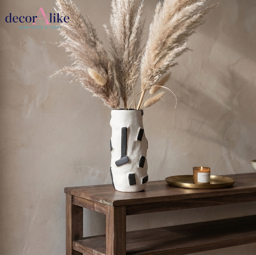 Modern white textured vase with black geometric accents styled with pampas grass on wooden console